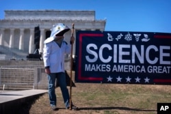 A protestor wearing a fish costume holds a sign as demonstrators gather for the Stand Up For Science rally near the Lincoln Memorial, March 7, 2025, in Washington.