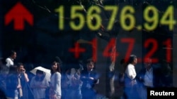 People are reflected in an electronic board outside a Tokyo brokerage, Sept. 19, 2013.