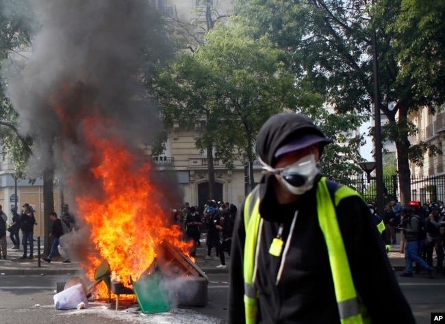 A man walks past garbage that was set on fire in Paris, May 1, 2019. Brief scuffles between police and protesters broke out in Paris as thousands of people gathered for May Day rallies under tight security measures.