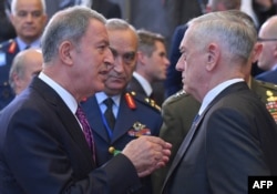 FILE - Turkish Defense Minister Hulusi Akar, left, speaks with U.S. Defense Secretary Jim Mattis prior to a defense ministerial meeting at NATO headquarters in Brussels, Oct. 4, 2018.