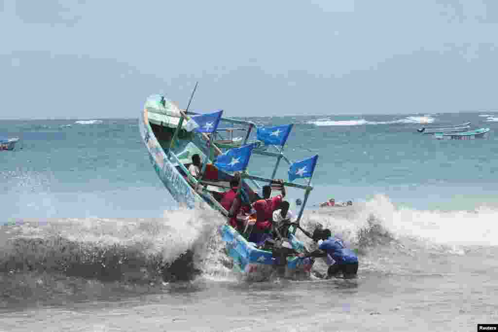 Para pengunjung menaiki perahu saat ombak besar melanda perairan Samudra Hindia di pantai Liido di Mogadishu, Somalia. (Reuters)&nbsp;