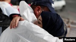 A Syrian migrant embraces a rescuer before disembarking from the Malta-based NGO Migrant Offshore Aid Station (MOAS) ship Phoenix after it arrived with migrants and a corpse, in Catania on the island of Sicily, Italy, May 6, 2017.