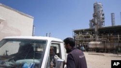A Libyan worker chats with two rebels in a vehicle as they patrol an oil refinery controlled by anti Gadhafi forces on the western outskirt of Zawiya city, Libya, August 19, 2011