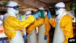 Guinea's health workers wearing protective suits join members of the Medecins sans frontieres Ebola treatement center near the main Donka hospital in Conakry on Sept. 25, 2014. 