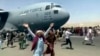 Des centaines de personnes courent le long d'un avion de transport C-17 de l'US Air Force à l'aéroport international de Kaboul, en Afghanistan, lundi 16 août 2021.