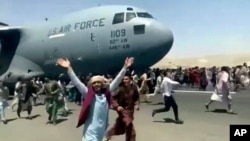 Des centaines de personnes courent le long d'un avion de transport C-17 de l'US Air Force à l'aéroport international de Kaboul, en Afghanistan, lundi 16 août 2021.