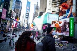 Para pengunjung mengenakan masker saat berada di Times Square, New York, 10 Desember 2020.