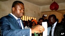 President of Togo Faure Gnassingbe (à gauche) place un bulletin de vote dans l'urne lors de l'élection présidentielle, à Lomé, le 25 juillet 2013