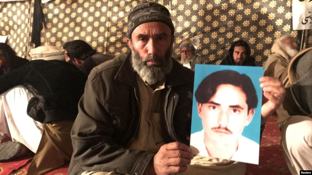 A member of Pakistan's Pashtun community holds a picture of Naqibullah Mehsud, whose extrajudicial killing by Karachi police in January sparked nationwide protests. 
