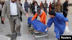 Medical personnel wheel body of victim killed by suicide bomber in Tuz Khurmato city, Jan. 23, 2013
