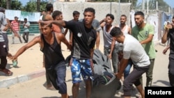 People carry a casualty at the site of what Palestinians say was an Israeli strike at a tent camp in Khan Younis in the southern Gaza Strip, July 13, 2024.