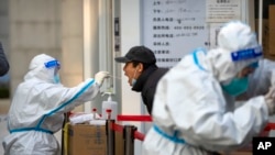 Seorang petugas kesehatan tampak melakukan tes usap COVID-19 kepada seorang pria di salah satu lokasi tes di Beijing, pada 17 November 2022. (Foto: AP/Mark Schiefelbein)