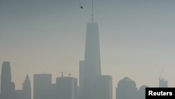 FILE - A helicopter flies over the Hudson River with One World Trade Center and Lower Manhattan in the background, in New York City, Dec. 6, 2015. 