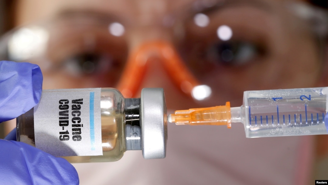 FILE - A woman holds a small bottle labeled "Vaccine COVID-19" and a medical syringe in this illustration taken April 10, 2020. 