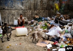 A man waits to get some food at a garbage dump in Las Minas de Baruta neighborhood, Caracas, Venezuela, on March 14, 2019.