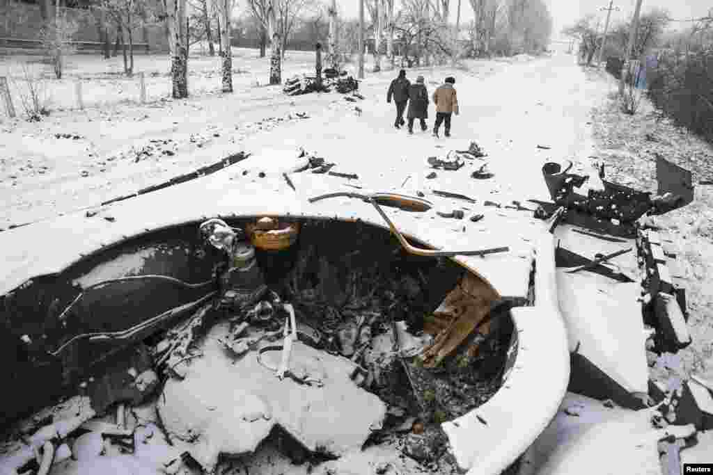 Locals walk past a destroyed Ukrainian army armored personnel carrier in the town of Vuhlehirsk, about 10 km west of Debaltseve, Feb. 16, 2015.