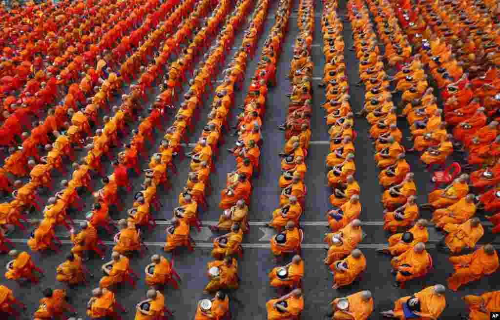 Biksu Buddha memegang mangkok dan duduk di kursi sebelum warga sipil memberikan makanan kering ke mangkok mereka di Bangkok, Thailand. Ribuan biksu Buddha berpartisipasi dalam acara yang diselenggarakan oleh pemerintah dan sektor swasta yang bertujuan mengumpulkan makanan untuk para biksu dan pegawai negeri yang bekerja di provinsi yang sedang bermasalah di Pattani selatan, Yala, Narathiwat dan Songkhla.