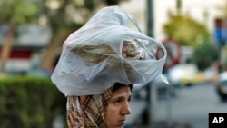 FILE - A woman carries bread on her head in Damascus, Syria, July 24, 2019. In October 2020, the government limited the amount of subsidized bread families could buy. And the market price of bread increased 26% from September to October.
