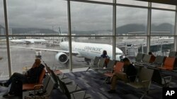 FILE - Travelers wait in a departure hall as an aircraft operated by Cathay Pacific Airways is seen at Hong Kong International Airport in Hong Kong, Oct. 8, 2023.