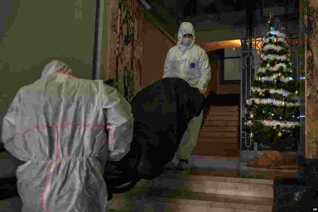 Mortuary workers remove the body of an elderly person who died of COVID-19 from a nursing home in downtown Barcelona, Spain.