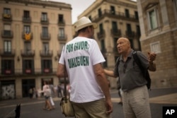 A man, wearing a t-shirt reading in Spanish: "Please, talk" chats with a passer-by about the current political situation in Catalonia, in Barcelona, Oct. 6, 2017.