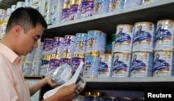 Staf penjualan Abbott Laboratories memeriksa nomor seri kaleng susu bubuk selama penarikan produksi di toko susu. (Foto: Reuters)