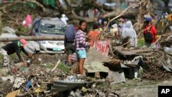 Seorang penyintas berdiri di tengah sampah di Tacloban, Filipina tengah (8/12). (AP/Aaron Favila)