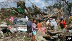 Para penyintas topan Haiyan berdiri di antara pohon-pohon yang roboh di Tacloban, Filipina, 8 Desember 2013 (Foto: dok).