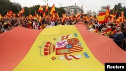 Manifestantes a favor de la unidad ondean la bandera española en la Plaza de Cibeles en Madrid.