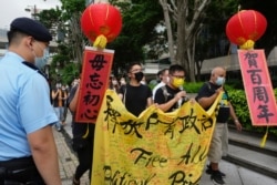 Four protesters carry a banner marching to the flag raising handover ceremony area in Hong Kong, July 1, 2021.