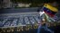 A demonstrator carries a Venezuelan flag as he runs next to a list of the victims of the violence during protests against Venezuela's president Nicolas Maduro government in Caracas, Venezuela, June 12, 2017.