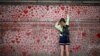 A woman draws on the National Covid Memorial Wall on the embankment on the south side of the River Thames in London.