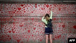 A woman draws on the National Covid Memorial Wall on the embankment on the south side of the River Thames in London.