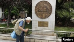 A man makes his way past a replica of a one drachma coin outside the Athens Town Hall, May 21, 2012.