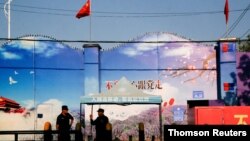 FILE - Security guards stand at the gates of what is officially known as a vocational skills education centre in Huocheng County.