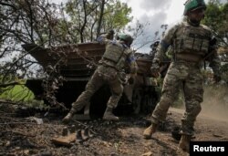 Ukrainian service members check a destroyed Russian a BMP-2 infantry fighting vehicle in the newly liberated village Storozheve