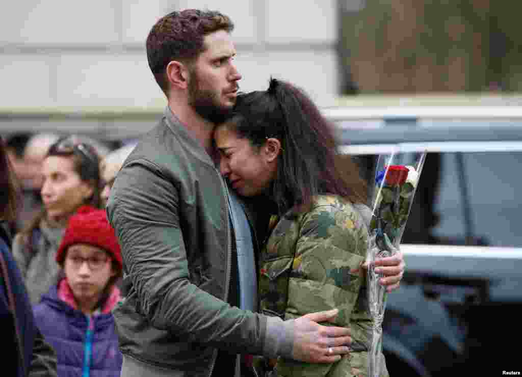 People react as they observe a minute&#39;s silence in memory of the victims of the Paris shootings, at the French Embassy in London.