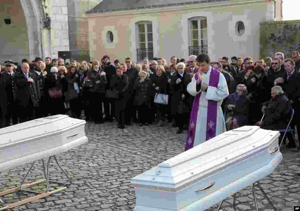 Seorang pendeta memberkati peti mati kakak adik, Marion dan Anna Petard, di Blois, Perancis tengah. Dua bersaudara tersebut tewas ketika sedang makan malam di cafe pinggir jalan dalam serangan maut di Paris, 13 November.
