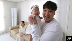 Lee Dong Kil holds his daughter Lee Yoon Seol as his wife Ryu Da Gyeong sits as they to celebrate daughter Lee's the 100th day of the birth at their house in Daejeon, South Korea, April 9, 2019.