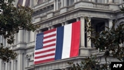 French and US flags hang on the Eisenhower Executive Office Building of the White House in Washington, Feb. 7, 2014.