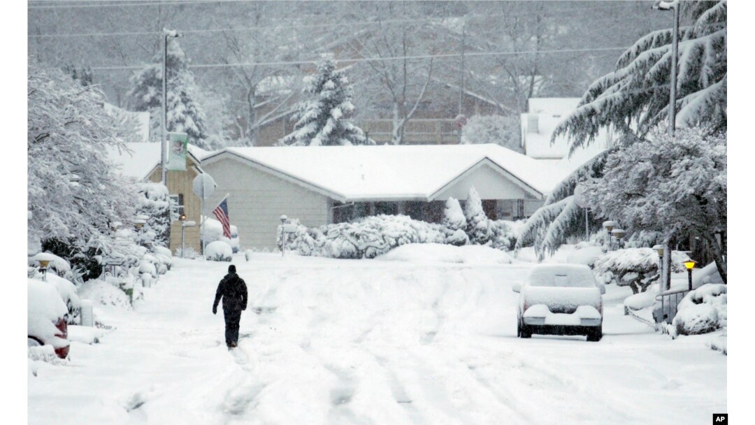 A lone figure walks down a snow covered street in King City, Oregon, Jan. 11, 2017.