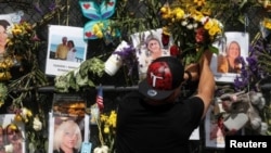 Un hombre coloca flores en un monumento improvisado para las víctimas del colapso del condominio Champlain Towers South en Surfside, al norte de Miami Beach, Florida, el 9 de julio de 2021.