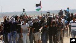 Palestinian protesters chant slogans while walking toward the fence during a protest at the Gaza Strip's border with Israel, Friday, May 11, 2018.