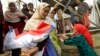 FILE - Indonesian women carry free food packages received from Indonesian President Joko Widodo during Ramadan in Jakarta, Indonesia, June 29, 2016. 
