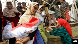 FILE - Indonesian women carry free food packages received from Indonesian President Joko Widodo during Ramadan in Jakarta, Indonesia, June 29, 2016. 