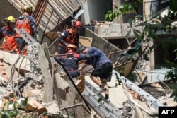 Para pekerja darurat membantu seorang korban yang telah diselamatkan dari bangunan yang rusak di Kota New Taipei, setelah gempa besar melanda bagian timur Taiwan. (Foto: AFP)