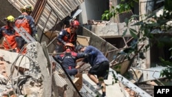 TOPSHOT - This photo taken by Taiwan's Central News Agency (CNA) on April 3, 2024 shows emergency workers assisting a survivor after he was rescued from a damaged building in New Taipei City, after a major earthquake hit Taiwan's east.
