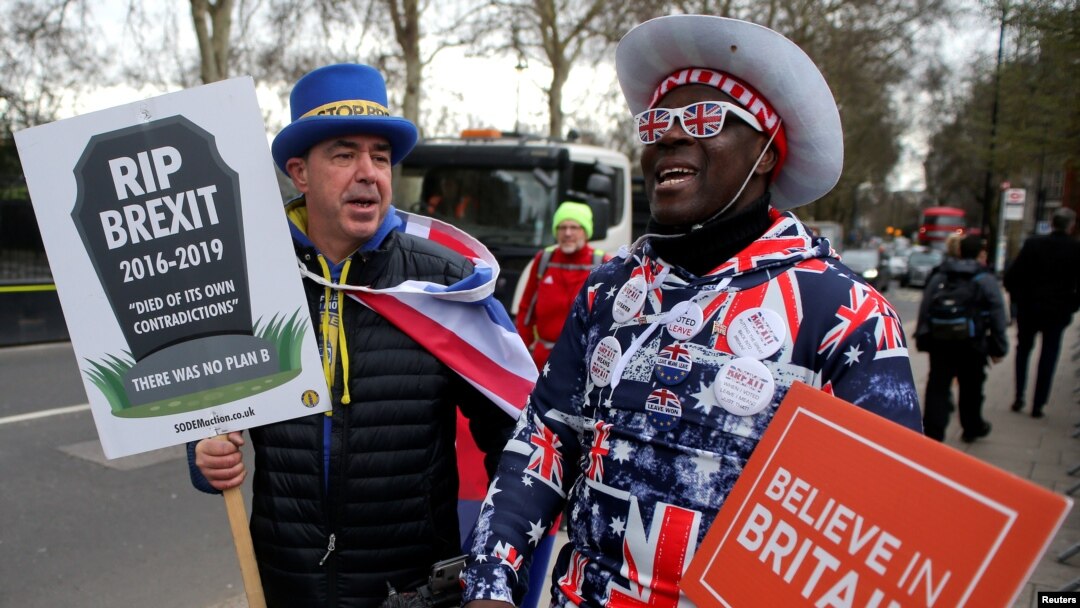 FILE - A pro-Brexit protester stands with anti-Brexit campaigner Steve Bray outside the Houses of Parliament in London, March 13, 2019. 