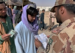 A Pakistani paramilitary soldier checks travel documents of an Afghan before crossing the border into Afghanistan through a common border crossing point in Chaman, Pakistan, Aug. 26, 2021.