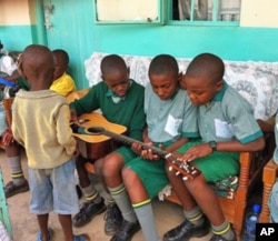 Children at the Divine Providence Children's Home in Kakamega, Kenya, examine a guitar.